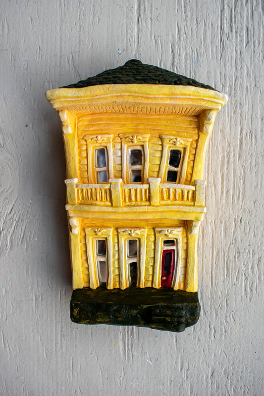 A plaster-molded facade styled to look like the distinct and unique two-story homes of New Orleans. Yellow Balcony-Style.